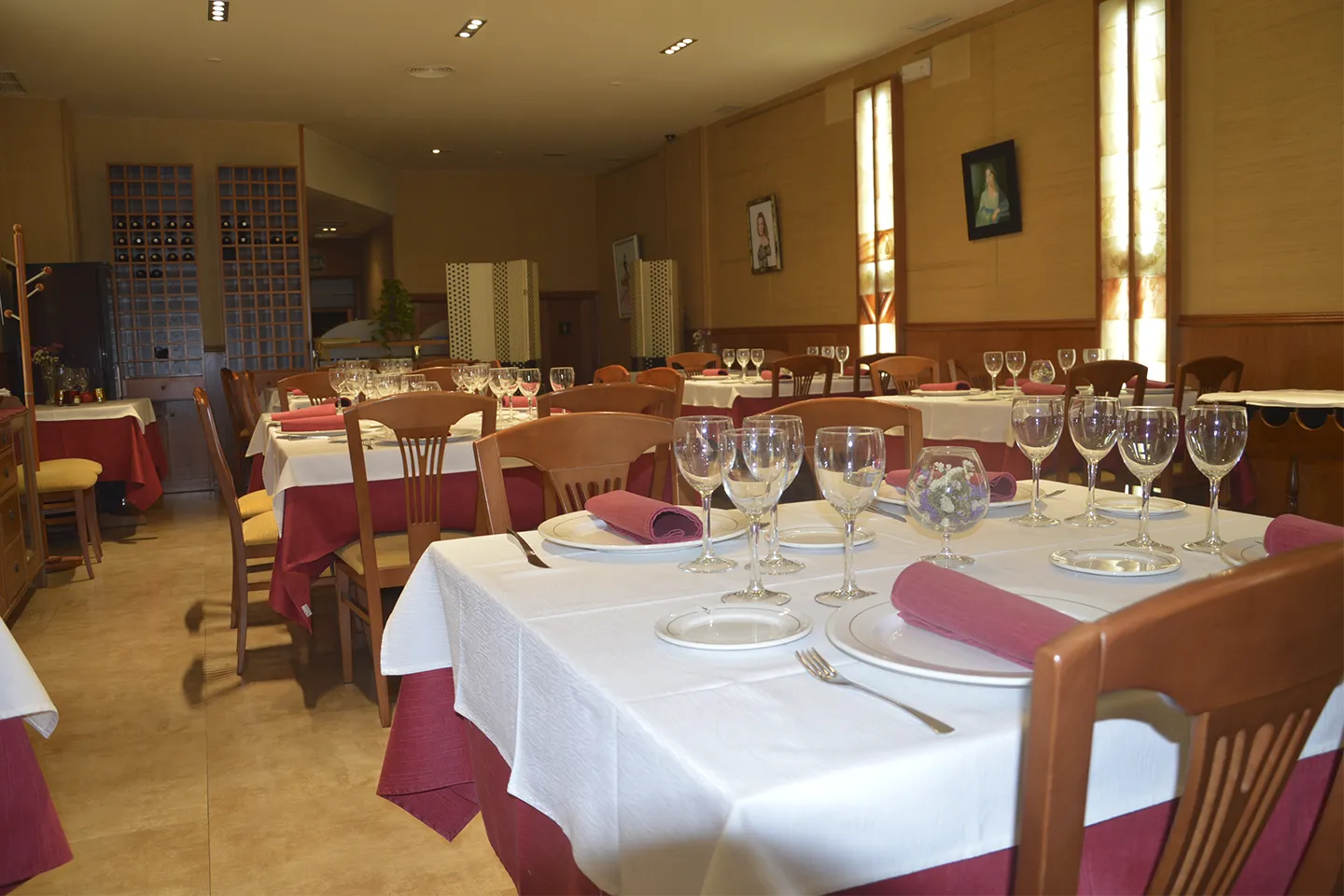El salón de V. Arranz, con mesas vestidas de blanco y burdeos y luz cálida en las paredes